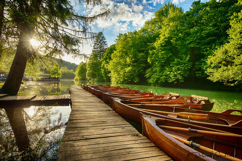 Beautiful sunlight along dock and wooden rowboats at Plitvice Lakes National Park in Croatia.