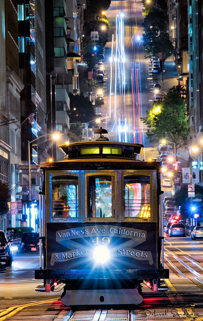 Cable car at night with streaks of light from passing cars.